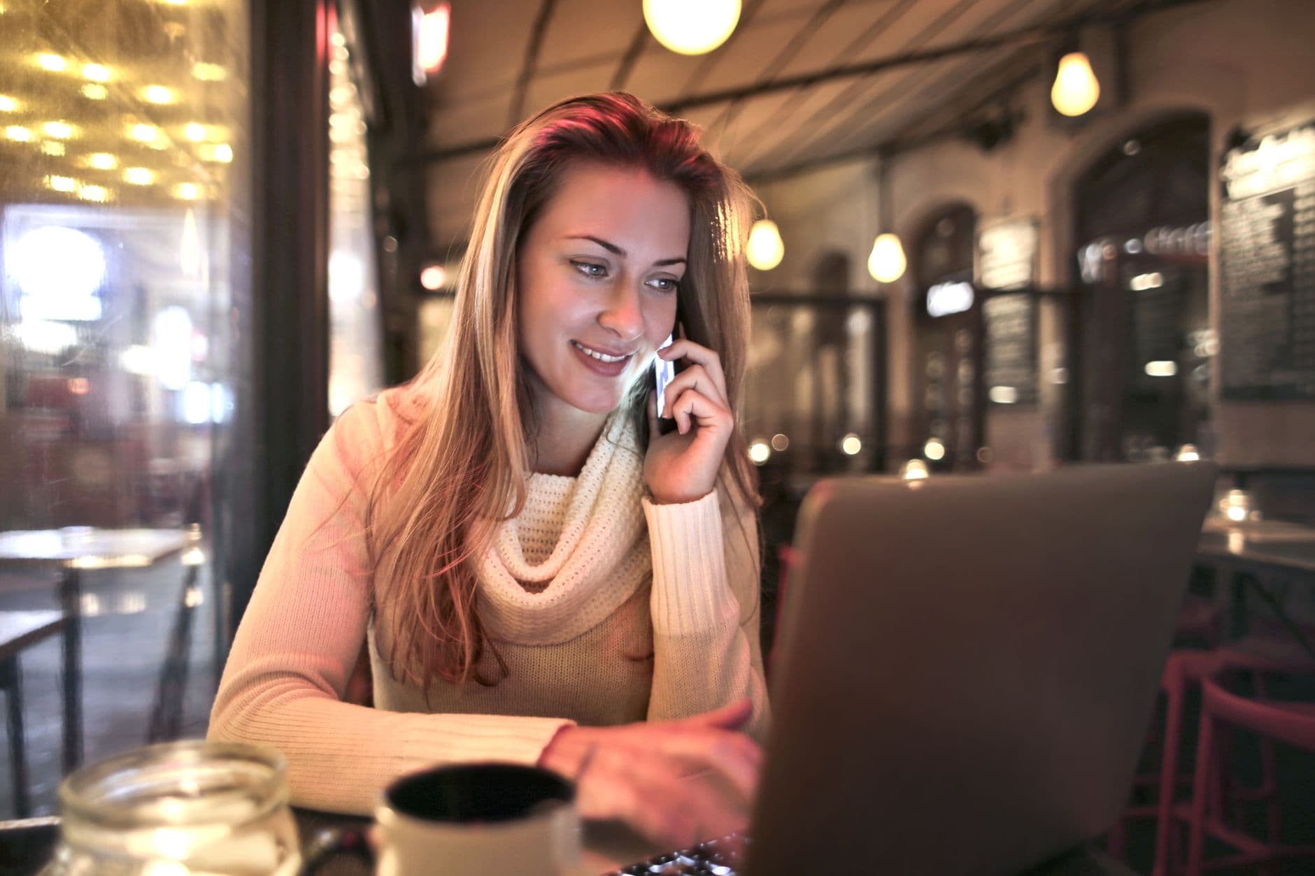 Une personne suit une formation sur son ordinateur portable, une tasse de café à côté, dans un café lumineux